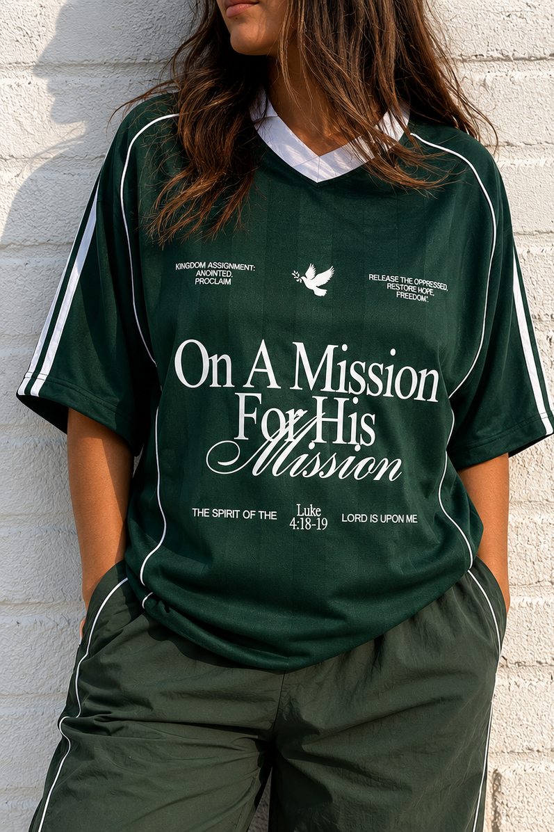 Green sports outfit with 'On A Mission For His Mission' text worn by a person against a white brick wall.