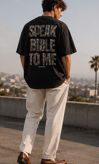 Person wearing a black t-shirt with text, standing outdoors.