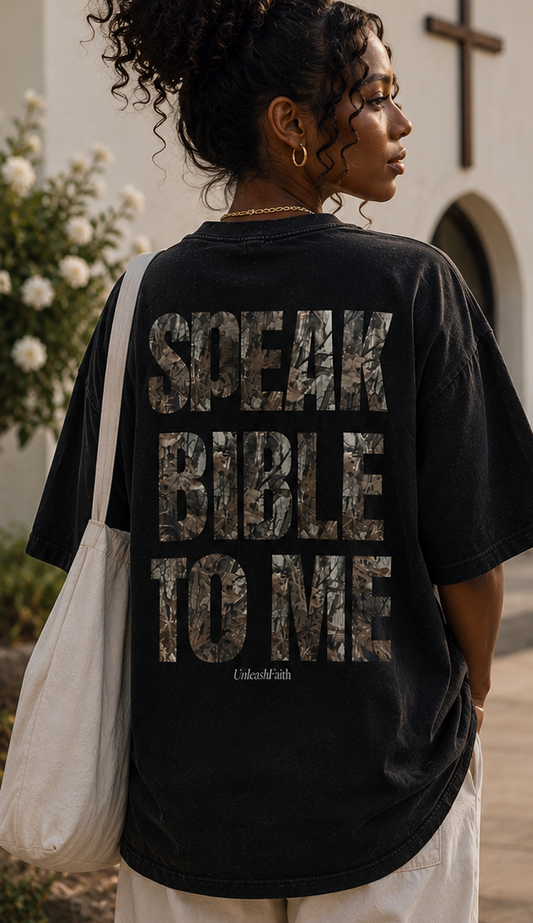 Woman wearing a black t-shirt with text, standing outdoors with a cross in the background.