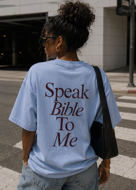 Woman wearing a light blue t-shirt with 'Speak Bible To Me' text, standing outdoors.